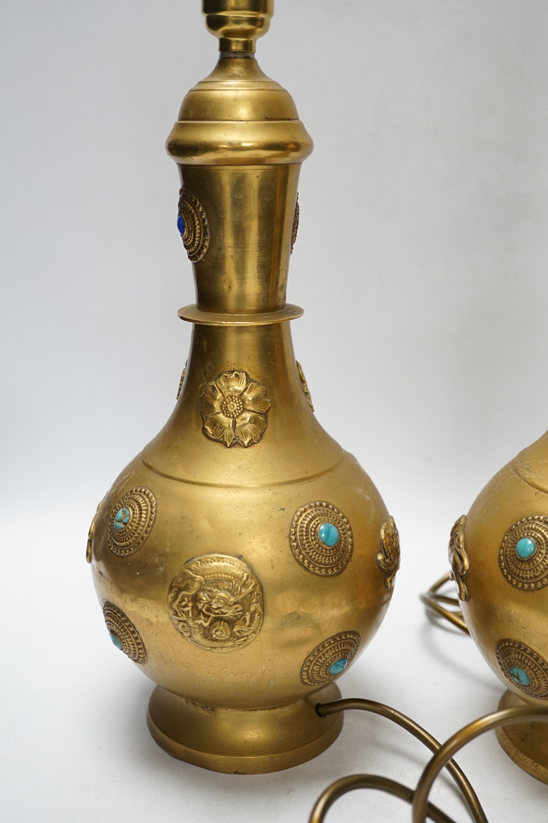 A pair of Sino-Tibetan gilt metal lamp bases set with cabochon stones